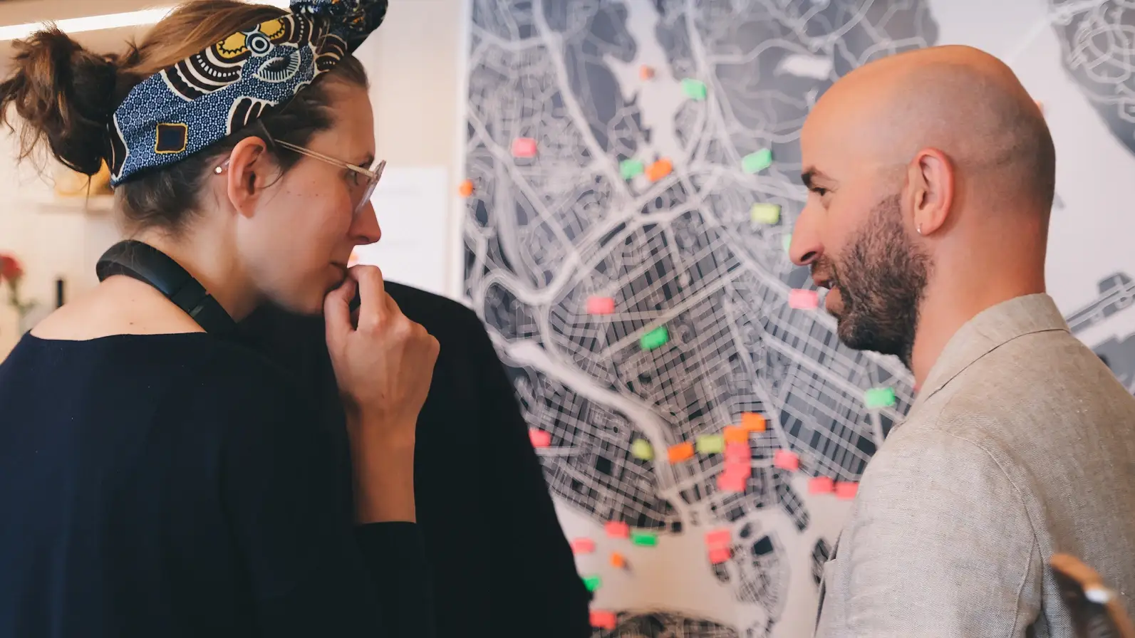 Two people talking in front of a map.
